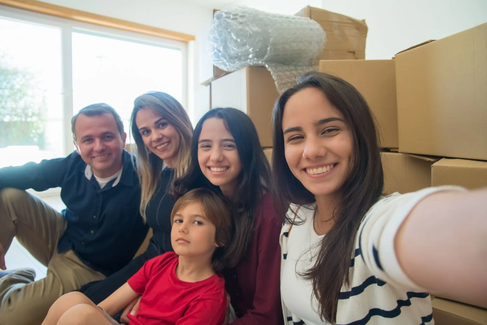 Parents and three children smiling together among moving boxes in their new home