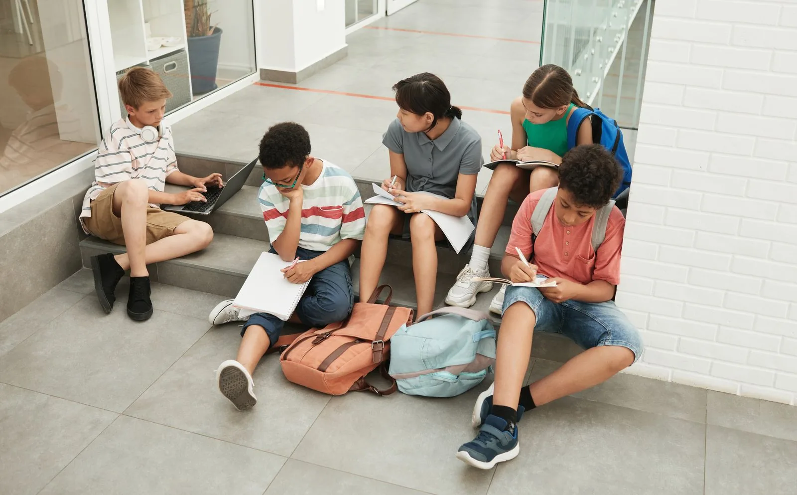 International school students working together on the stairs of a modern school building